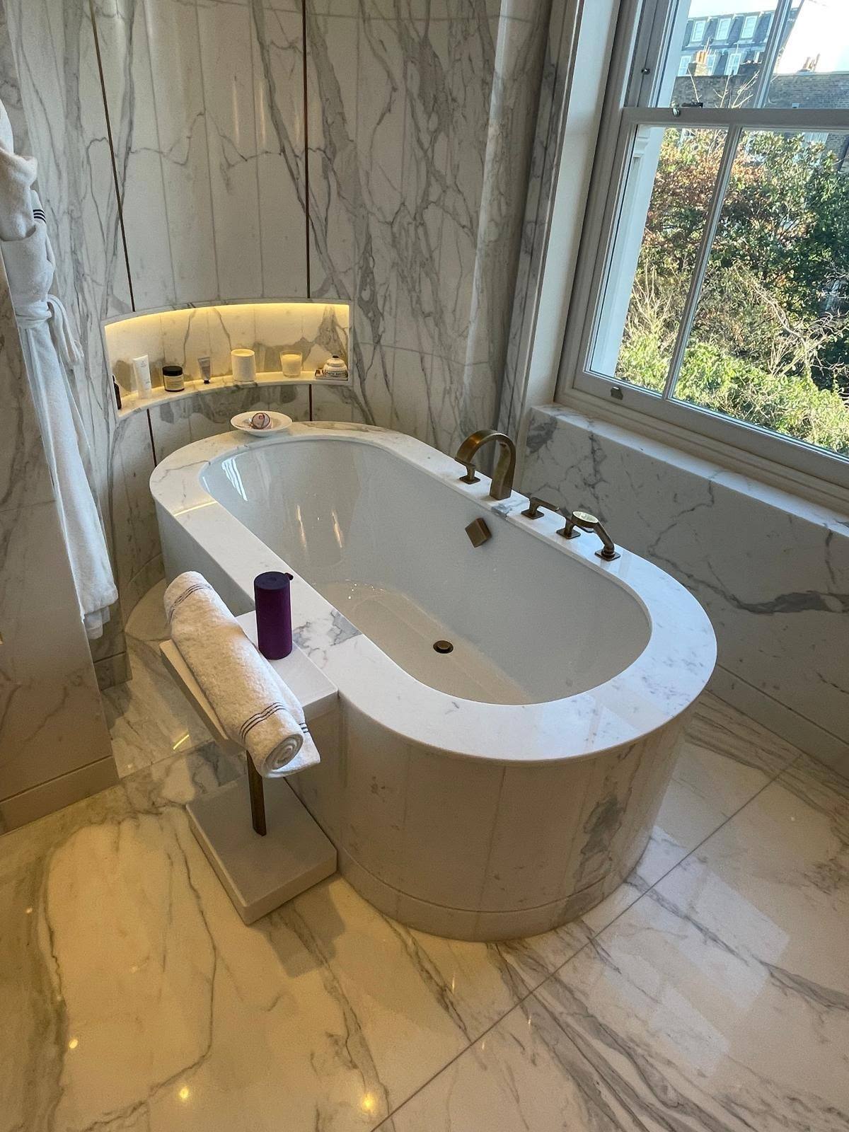 Marble bathroom with an oval bath sealed to the surrounding stone floor