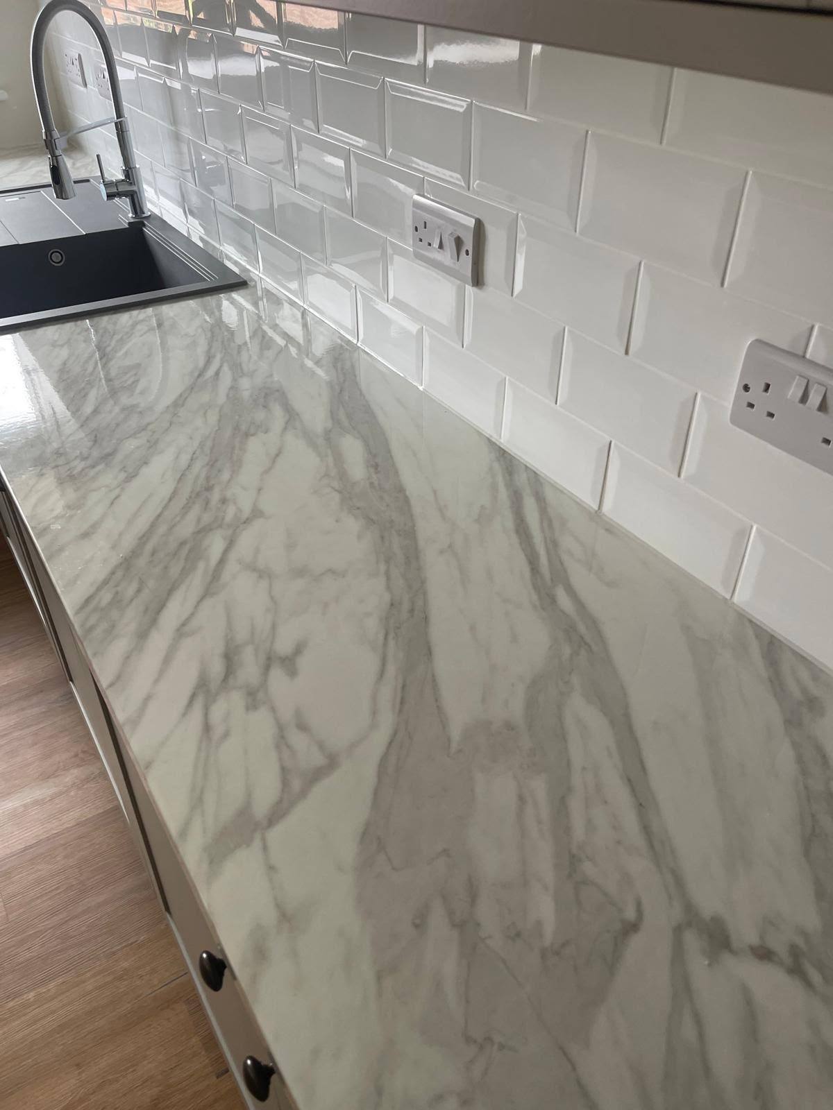 Marble worktop sealed to a white subway tile kitchen splashback