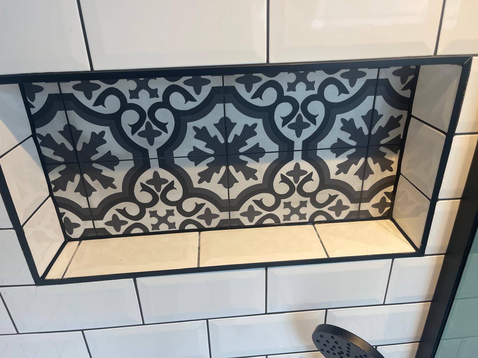 Patterned shower tile niche with black trim and neat silicone sealing
