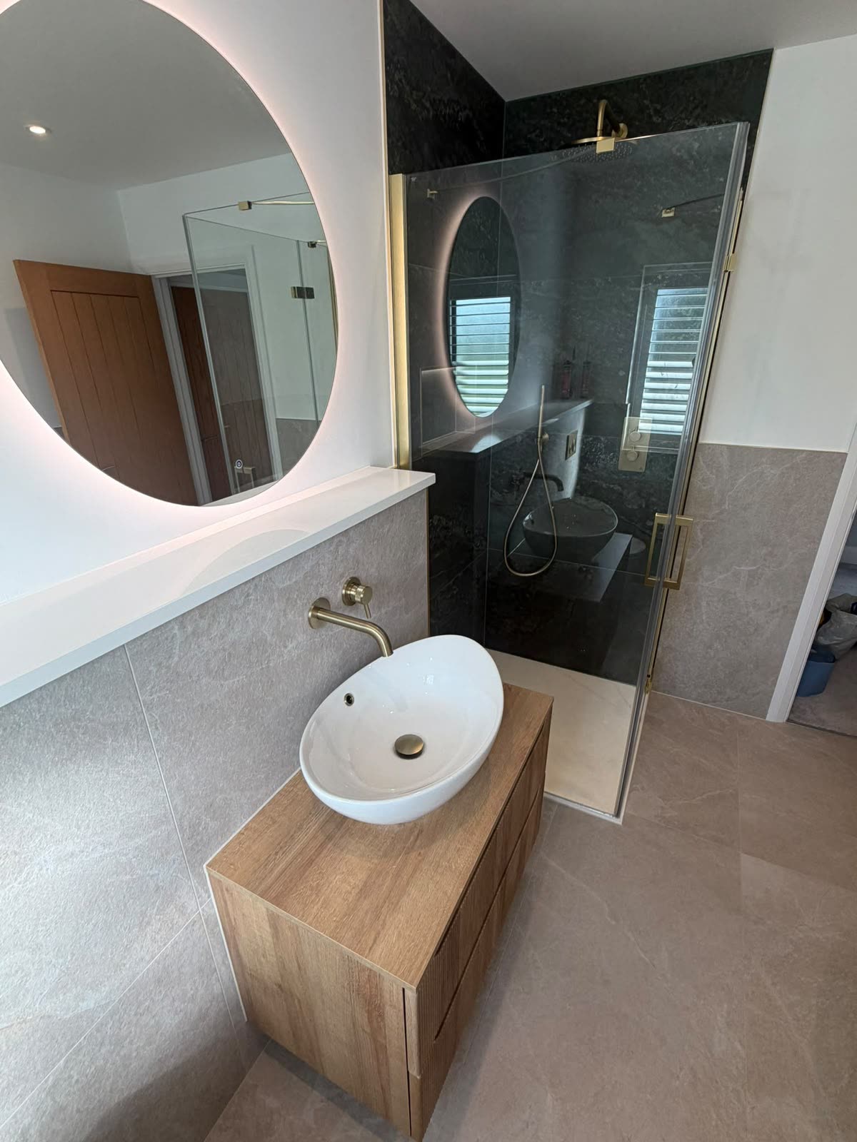 Bathroom with walk-in shower enclosure and wood vanity, shower tray and tiles neatly silicone sealed