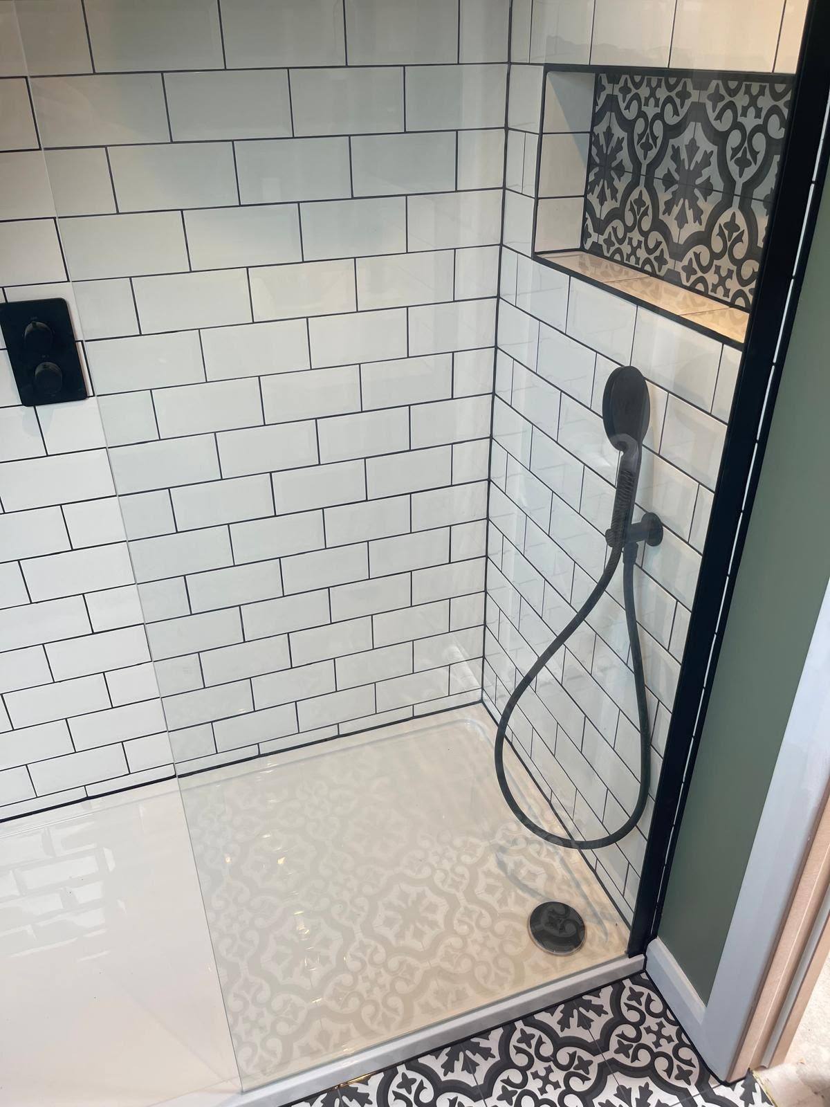 White subway tiled shower with a sealed decorative tile niche