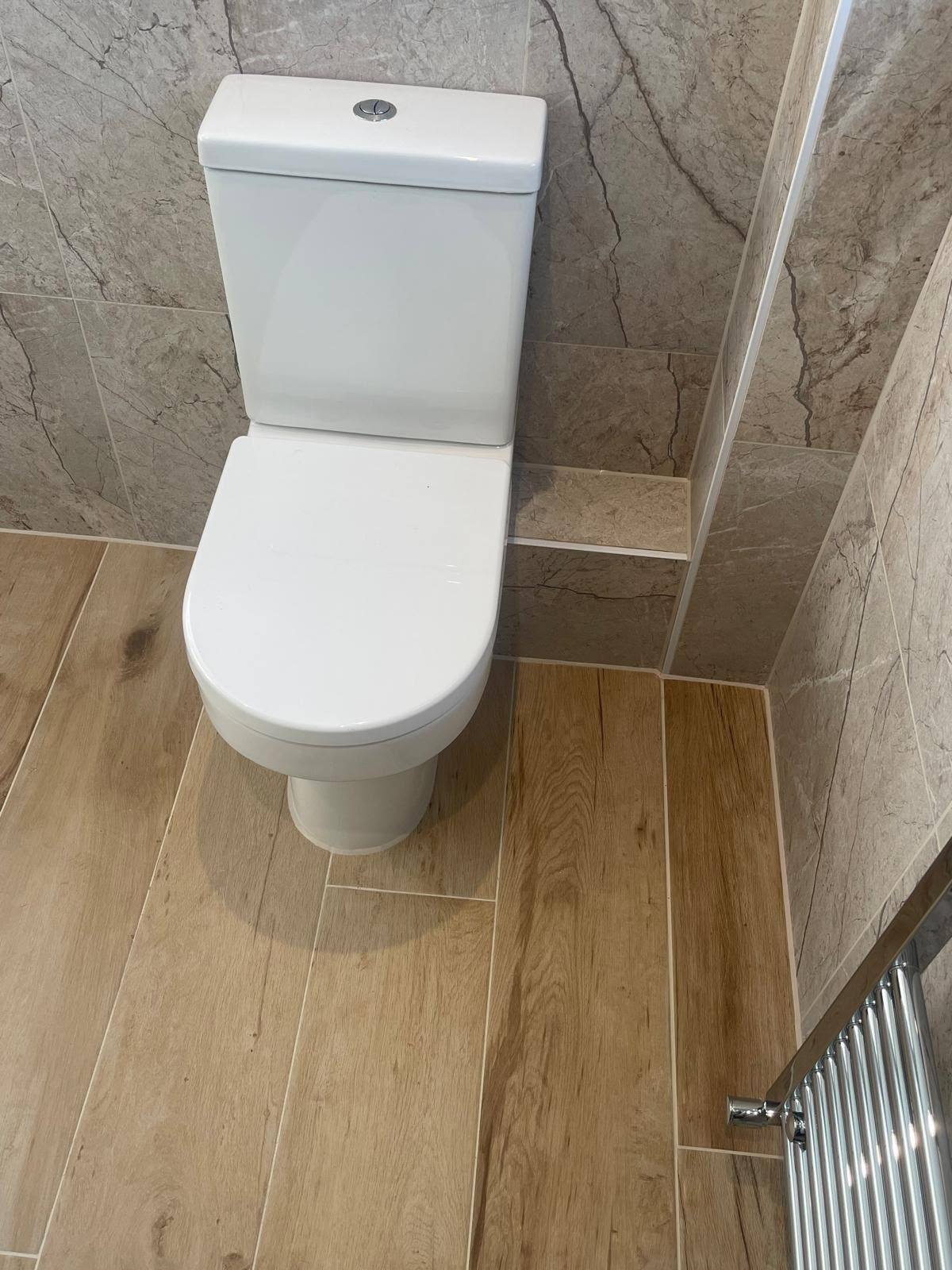 Toilet pan sealed to a wood-effect plank bathroom floor