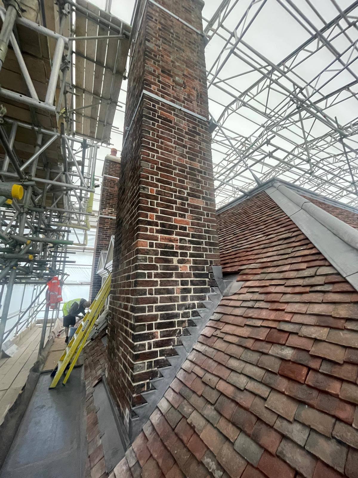 Scaffolded brick chimney before external weather sealing