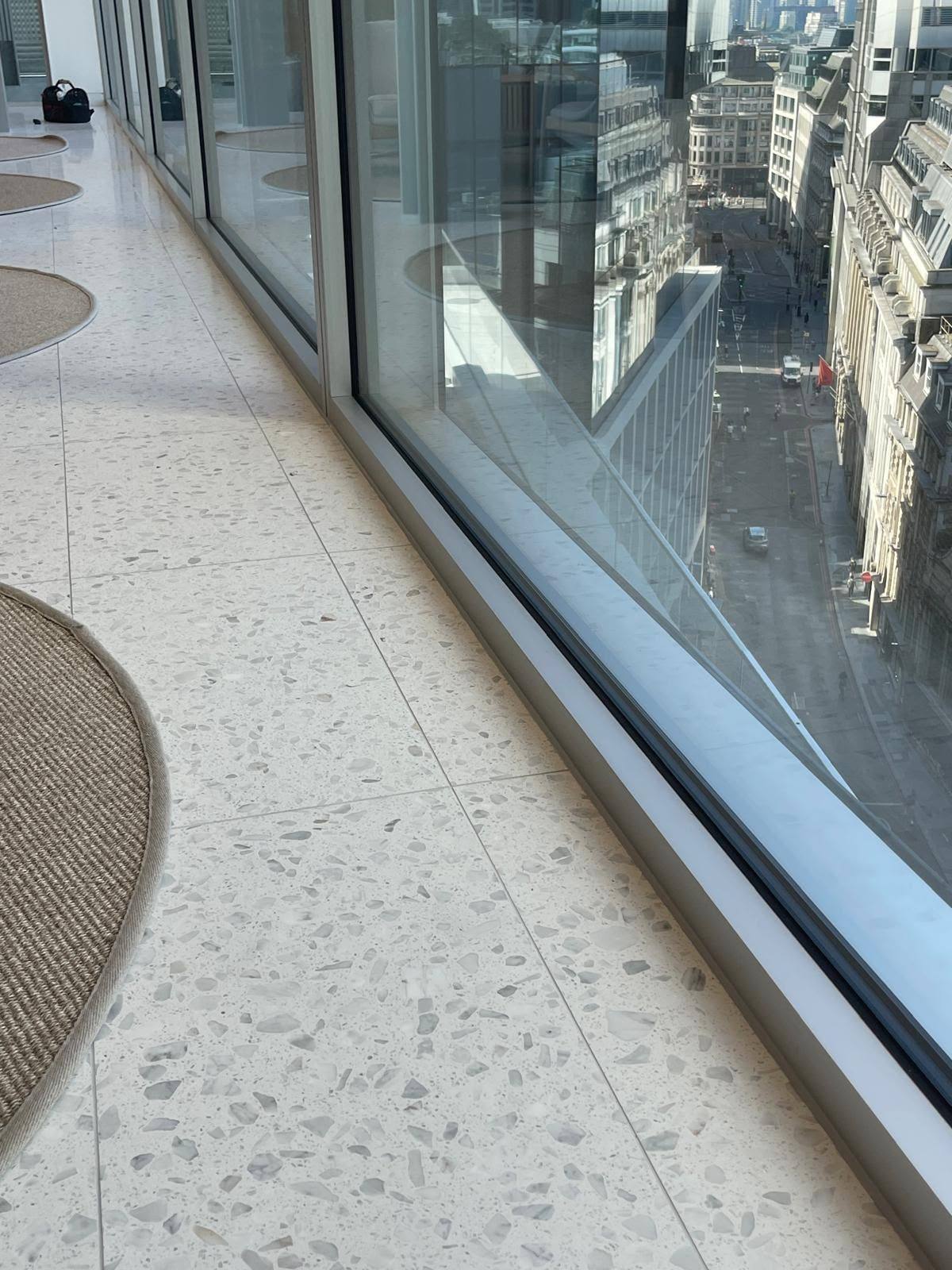 Glass curtain wall sealed to terrazzo flooring with a thin neat joint